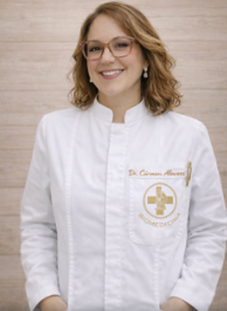Dra. Cármen Alvarez em jaleco branco com logo dourado bordado, em ambiente de laboratório